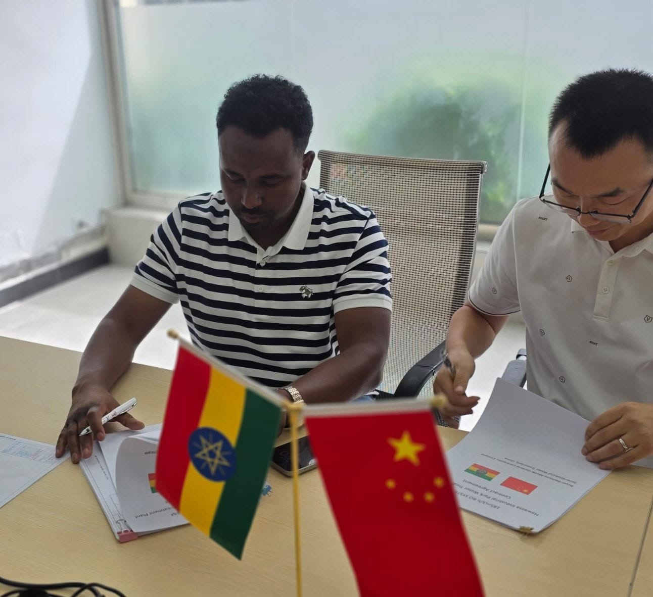 双方代表在会议桌前签署文件，桌上摆放中国和埃塞俄比亚国旗